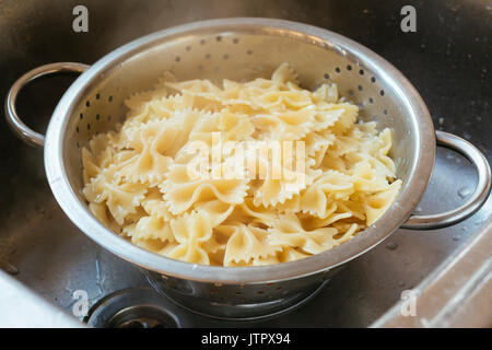 Cooked farfalle (bow-tie) pasta in a colander Stock Photo