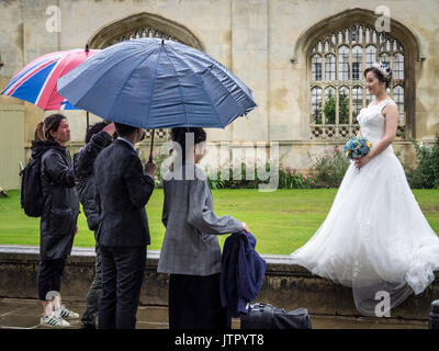 Chinese Wedding Tourism / Asian Wedding Tourism -  Asian Couple has pre-nuptual wedding photos taken in historic central Cambridge UK on a rainy day Stock Photo