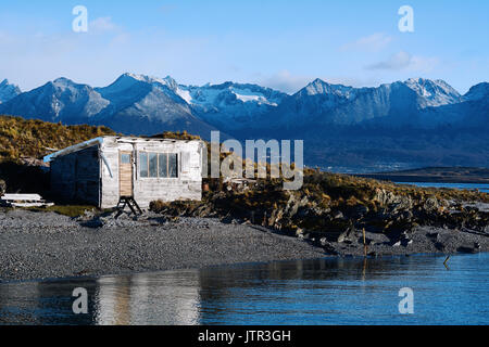 A wooden house near the river with mountains at back. Stock Photo