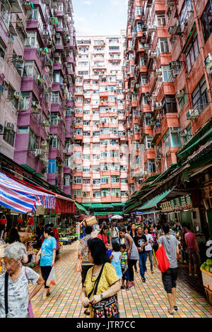 HONG KONG, JULY 6, 2017: A crowd of morning shoppers at a street market beneath the crowded apartments in Hong Kong's old residential district of Quar Stock Photo