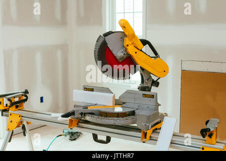 Carpenter cutting wooden plank with circular saw wearing safety equipment Stock Photo