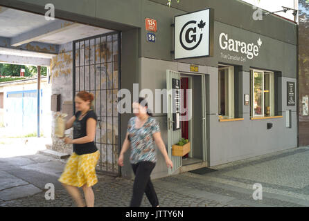 Prague, Czech Republic. 10th Aug, 2017. Passers-by walk past the fast food restaurant 'Garage', where Canadian specialties are on offer, in the Karlin district of Prague, Czech Republic, 10 August 2017. The restaurante is named after the garages in the backyard. The heavily hit district of Karlin has not only recovered 15 years after the catastrophe but it even enjoys a bone-fide boom. Photo: Michael Heitmann/dpa/Alamy Live News Stock Photo