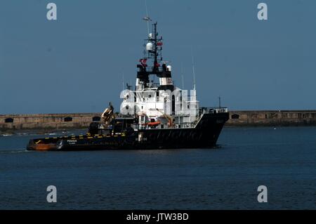 River Tyne, South Shields, UK, 10th August 2017. The tug Pegasus passing Tynemouth pier towing a barge carrying wind turbine foundations for the Beatrice offshore wind farm in the Moray Firth. Credit: Colin Edwards/Alamy Live News. Stock Photo