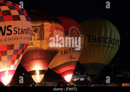 Hot air balloons at Bristol International Balloon Fiesta, held at Ashton Court, Bristol, UK, 10th August 2017. The balloons are rising for a Night Glow, an event designed to be less weather dependent, and in which the balloons stay on the ground as a group and light up using their gas flares in time to music. Stock Photo