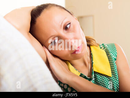 Depressed  middle-aged woman sitting on sofa Stock Photo