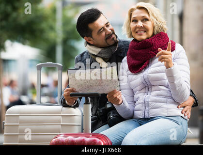 happy american mature couple with suitcases, camera and map outdoors Stock Photo