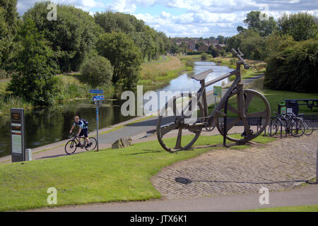 Cyclist on NCN 7 pass the Bankies bike sculpture at Clydebank  Summer weather returns and locals enjoy the summer  on the Forth and Clyde canal Stock Photo