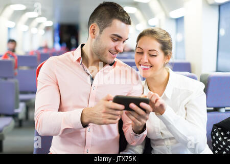 Portrait of smiling young couple with smartphones in train Stock Photo