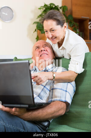 Happy elderly russian  man and mature woman using laptop at home Stock Photo