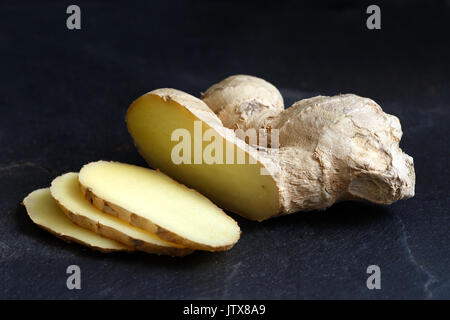 Sliced ginger root isolated on black slate. Stock Photo
