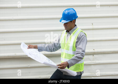 Portrait of a male Indian industrial engineer at work looking at technical drawing plans. Stock Photo