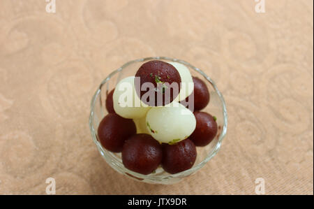 Gulab Jamun and Rasgulla lying over one another in a glass bowl Stock Photo