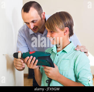 Happy man teaching son using electric drill at home Stock Photo