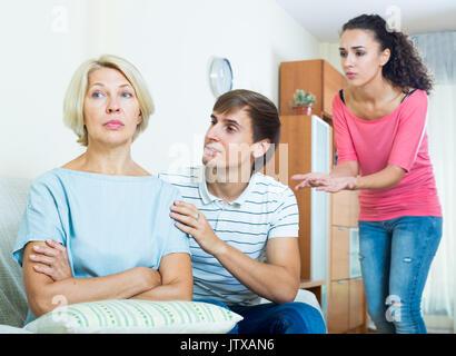 Frustrated woman watching how adults trying to reconcile with her Stock Photo
