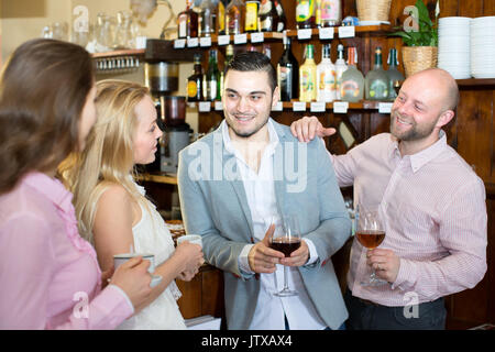 Portrait of a company of friends in a bar two men and two women are having a good time drinking coffee and wine Stock Photo