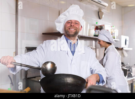 Cheerful professional chefs working in restaurant kitchen Stock Photo