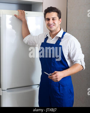 portrait of serviceman fixing technical problems with fridge at residential lot Stock Photo
