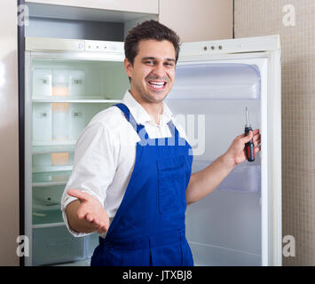 adult serviceman fixing technical problems with fridge at residential lot Stock Photo