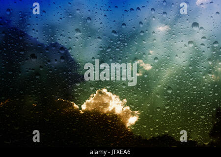 Looking through a misty window with raindrops at storm clouds Stock Photo