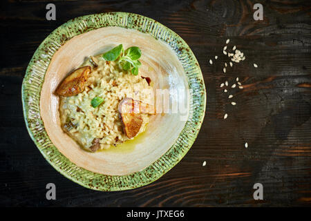 Risotto with chicken, peas and tomatoes on a wooden board, Italian Stock Photo
