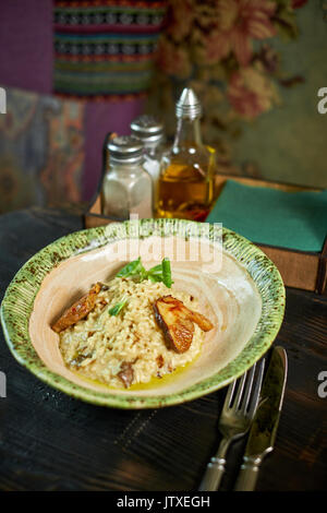 Risotto with chicken, peas and tomatoes on a wooden board, Italian Stock Photo