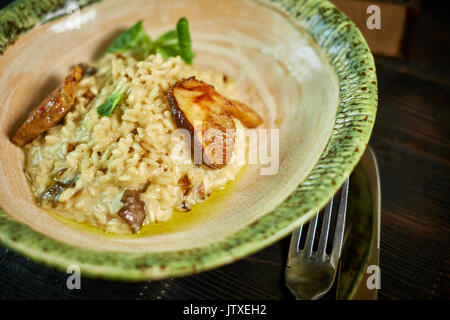 Risotto with chicken, peas and tomatoes on a wooden board, Italian Stock Photo
