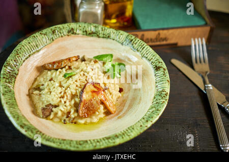 Risotto with chicken, peas and tomatoes on a wooden board, Italian Stock Photo