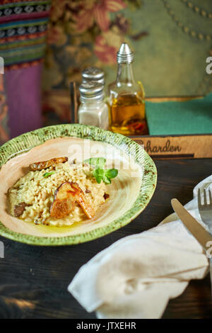 Risotto with chicken, peas and tomatoes on a wooden board, Italian Stock Photo