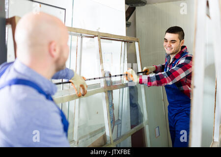 Two smiling production workers in coverall working with different PVC window Stock Photo