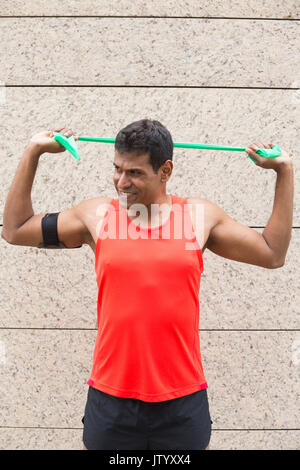 Portrait of an athletic Indian man using stretch bands outdoors in urban setting. Stock Photo