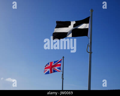 The Cornish cross of St Piran flies alongside the Union flag at Fistral, Newquay, Cornwall. Stock Photo