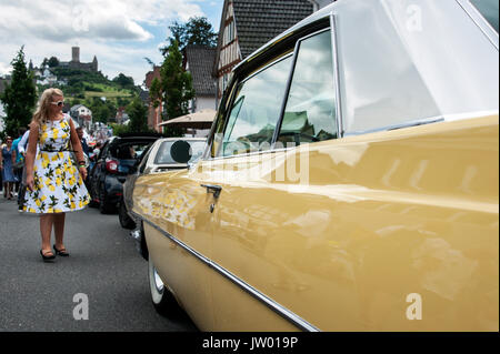 Vintage Car Festival 'Golden Oldies', Woman dressed in fifties look and a yellow vintage car on the main street below the castle. Stock Photo