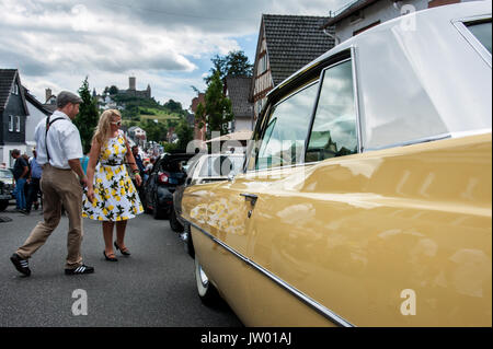 Vintage Car Festival 'Golden Oldies', Woman dressed in fifties look and a yellow vintage car on the main street below the castle. Stock Photo