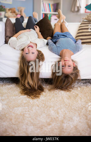Crazy girls lying upside down on the sofa Stock Photo
