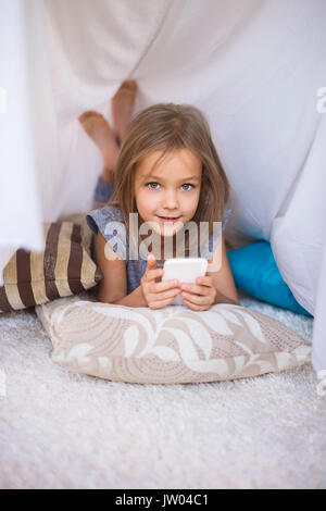 Girl lying on the front and using a mobile phone Stock Photo