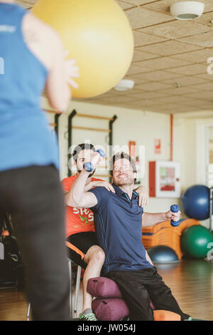 Young man practicing with dumbbells during physiotherapy session Stock Photo