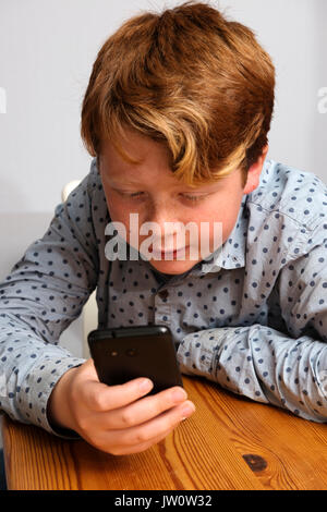 11-year old boy using smartphone to access social media Stock Photo