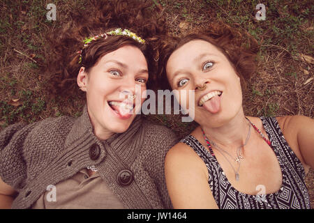 Two funny girls showing their tongues in nature Stock Photo