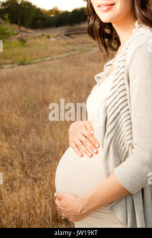 Pregnant woman ouside holding her belly Stock Photo - Alamy