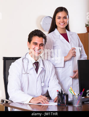 Two smiling doctors therapeutists with stethoscope posing in private clinic Stock Photo