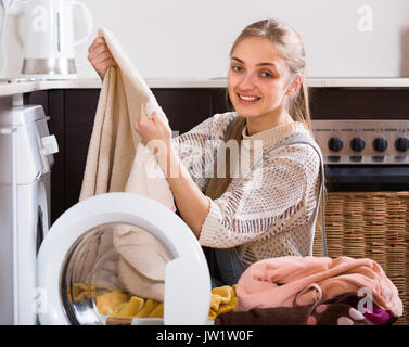 Smiling longhaired woman doing laundry in home interior Stock Photo