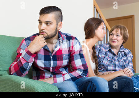 Mature woman comforts sad daughter  in living room Stock Photo