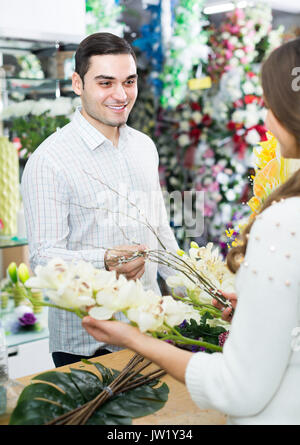 Woman seller 30s  helping to pick floral bouquet of flowers man at flower shop Stock Photo