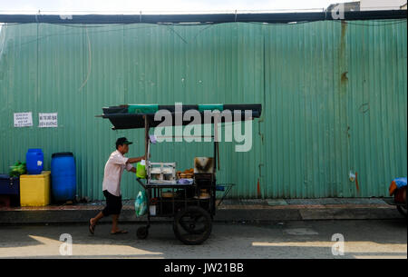 A male Vietnamese street vendor pushes his cart along a street in Ho Chi Minh City, Vietnam Stock Photo