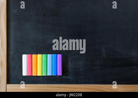 School board with a set of colored crayons. All colors of the rainbow Stock Photo