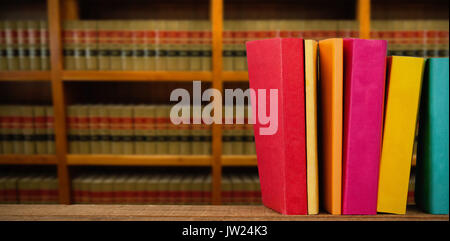 Colorful books arranged on table against bookshelf in school Stock Photo