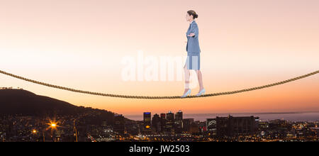 Businesswoman walking with arms outstretched over white background against view of the city by night Stock Photo