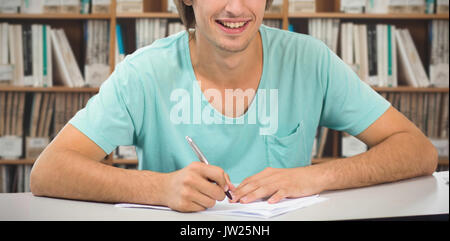 Student working against various multi colored books on shelf Stock Photo