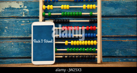Back to school text against white background against abacus with smart phone on table Stock Photo