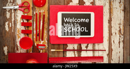 Welcome back to school text against white background against school supplies with digital tablet and apple on wooden table Stock Photo